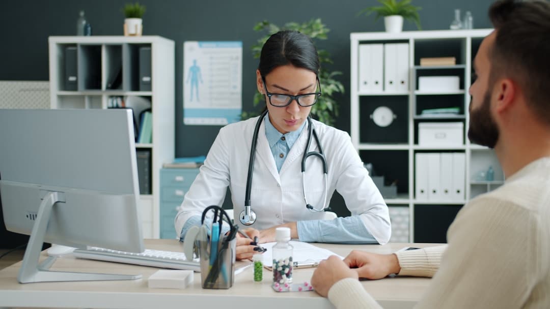 Médica especialista consultando paciente em consultório particular com computador na mesa